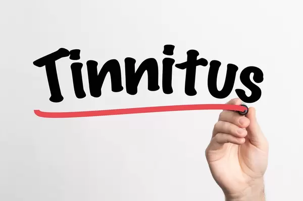 Human hand writing Tinnitus on whiteboard