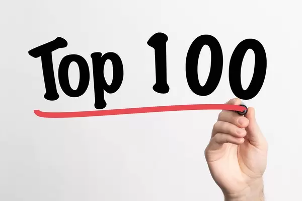 Human hand writing Top 100 on whiteboard