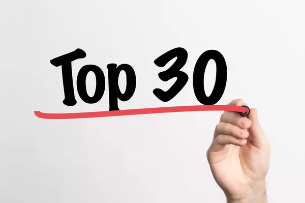 Human hand writing Top 30 on whiteboard