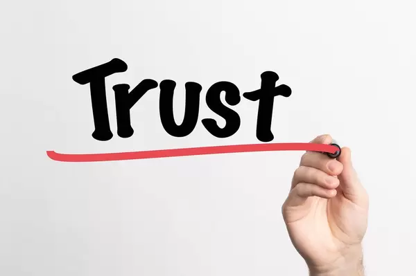 Human hand writing Trust on whiteboard