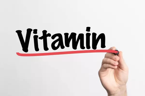 Human hand writing Vitamin on whiteboard