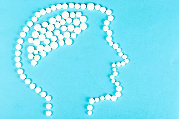 Human head made of pills on blue background