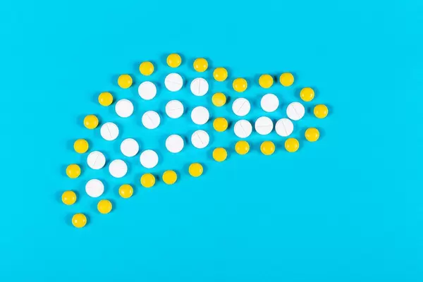 Human liver made from white and yellow pills on blue background