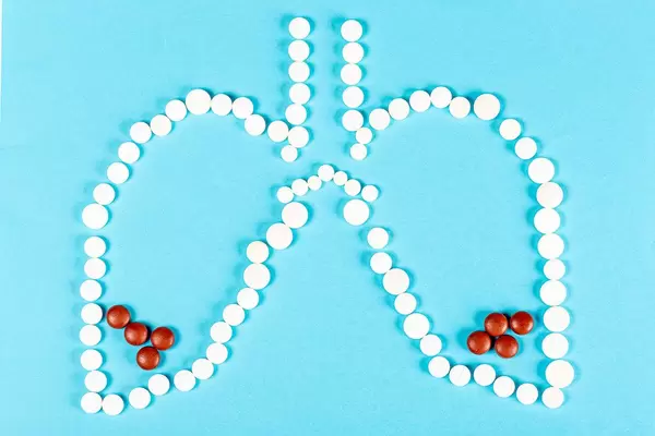 Human lungs made with white pills with brown pills at the bottom