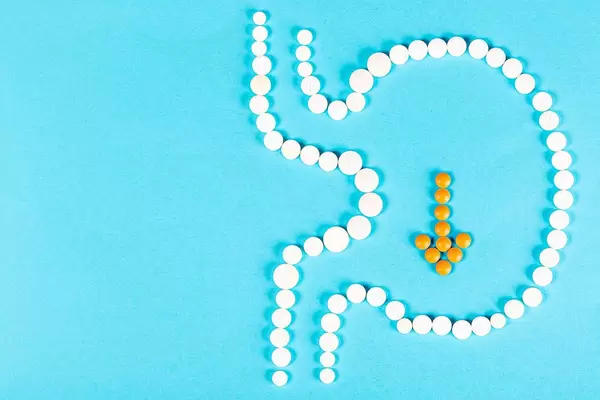 Human stomach made of pills with an arrow pointing down