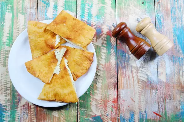 Hungarian Langos with cheese, salt and pepper on a colored vintage wooden background (Flip 2019)