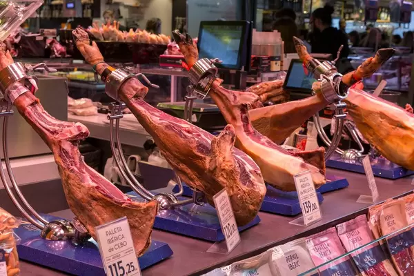 Iberischer Schinken vom Ibérico-Schwein mit Schweinefuß am Fleischstand in der Mercat de la Boqueria an der La Rambla in Barcelona, Spanien