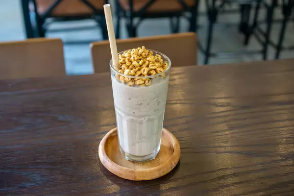 Ice Blended Cookies and Cream Milkshake with Puffed Rice Topping on a Wooden Saucer with Paper Straw