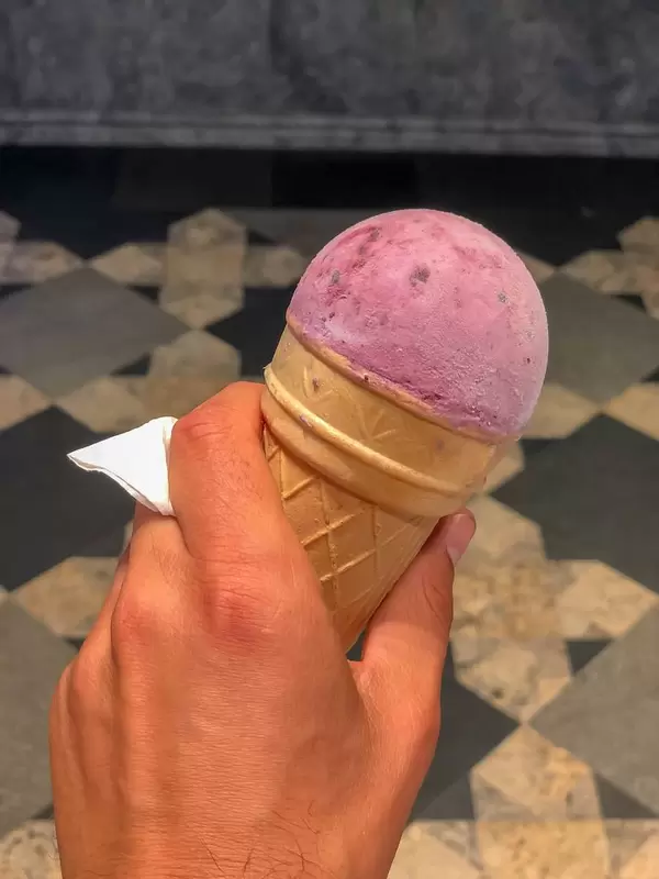Ice cream cone with a strawberry scoop in hand
