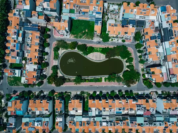 Identische Häuser in der Vogelperspektive mit einem kleinen See und Bäumen in einem Wohngebiet in Distrikt 7 mit einer Drohne fotografiert in Ho Chi Minh Stadt, Vietnam