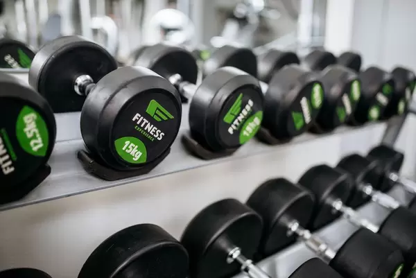 Im Regal sortierte Hanteln für Kraftübungen in Fitnessstudio