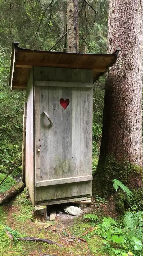 Im Wald in Alpbach: ein Outdoor-Klo aus Holz mit einem roten Herzen an der Tür