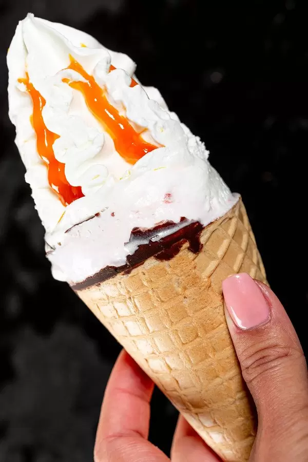 In a woman's hand a large ice cream on a black background