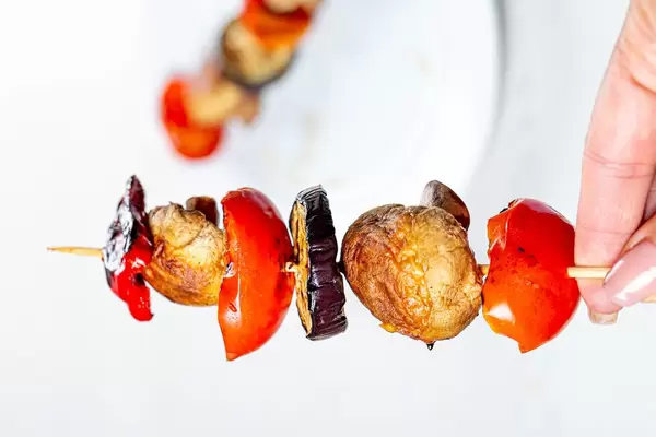 In a woman's hand a small wooden skewer with grilled vegetables (Flip 2019)
