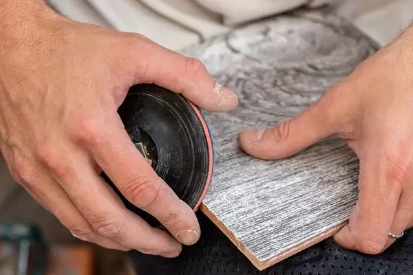 In hands of the master tile which is processed with the help of a grinding machine