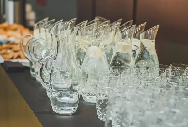 In Restaurant bereitgestelltes Trinkwasser mit Zitrone in Karaffen sowie Trinkgläser