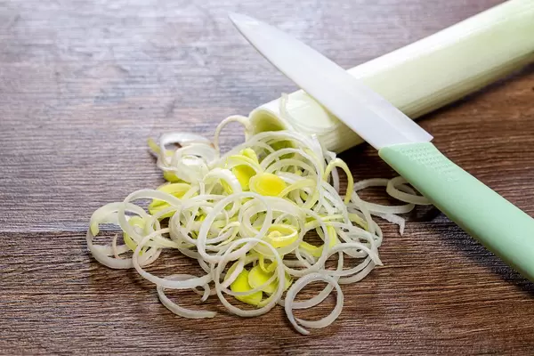 In Ringe geschnittene Lauch mit Messer auf einem Holztisch