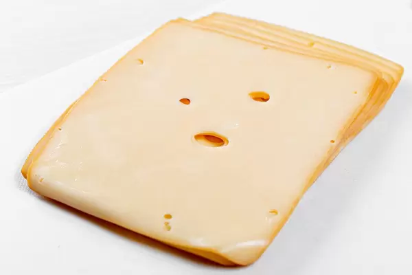 In Scheiben geschnittene, geräucherte Käse auf einem Schneidebrett