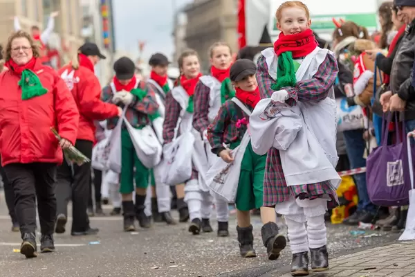 In weiße Kittel gekleidete Kinder werfen Zuschauern Süßigkeiten zu - Kölner Karneval 2018