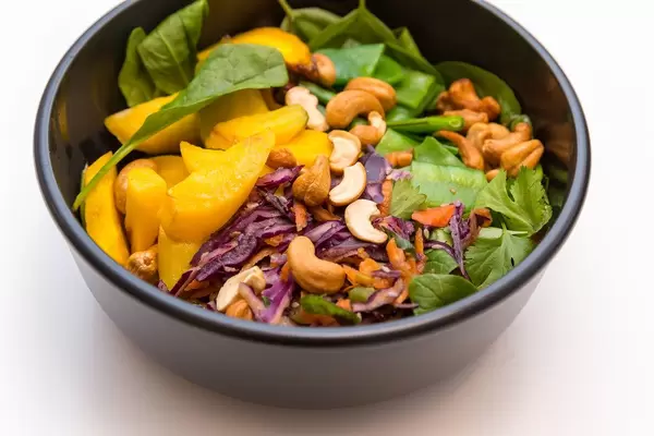 Indian Summer Bowl with leaf spinach, sugar peas, warm rosemary potatoes, raw vegetable salad, roasted yellow carrots, cashews, basil, coriander and yellow Thai curry sauce