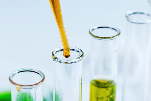 Indikator-Flüssigkeit tropft aus einer Pipette in ein Reagenzglas Nahaufnahme