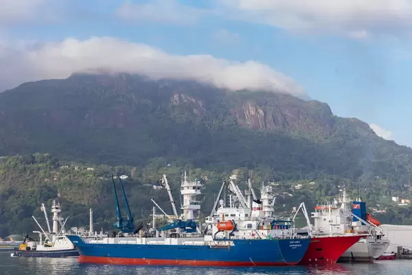 Industriehafen in Victoria auf Mahé, Seychellen mit angedockten Schiffen vor den grünen Hügeln der Insel
