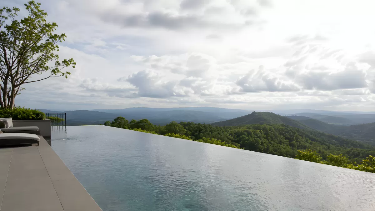 Infinity-Pool mit Panoramablick auf grüne Berglandschaft
