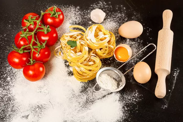 Ingredients for cooking fettuccine with raw eggs, tomato and flour