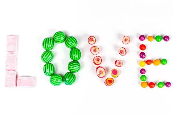 Inscription love from multi-colored sweets on a white background