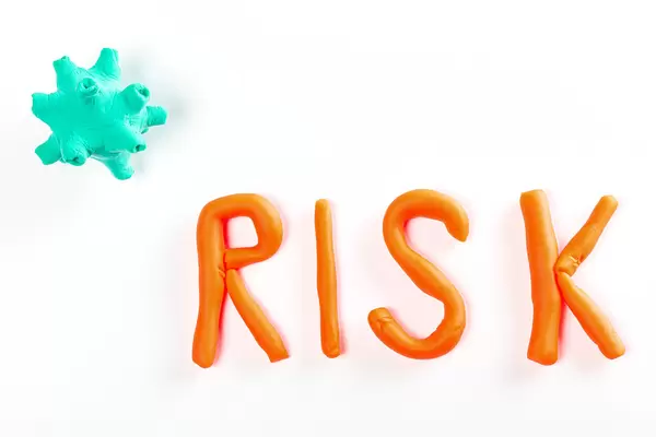 Inscriptions risk and model of coronavirus made from plasticine on white, top view