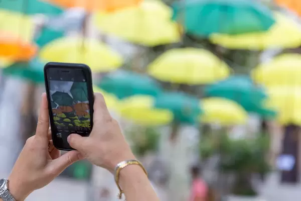 Installation in Sóller: Hände einer Frau, die mit dem iPhone Víctor Balaguers Regenschirmen fotografiert