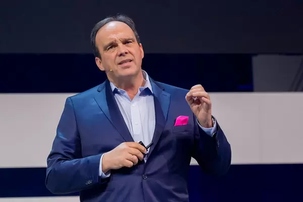 Intense facial expression during a keynote presentation: Hagen Rickmann (Deutsche Telekom) in a blue suit with magenta handkerchief - the colour of his company's brand
