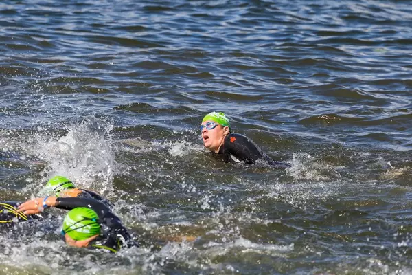 Ironman-Athleten, mit Badekappen und Schwimmbrillen, beim Kraulschwimmen im finnischen See Vesijärvi in Päijät-Häme