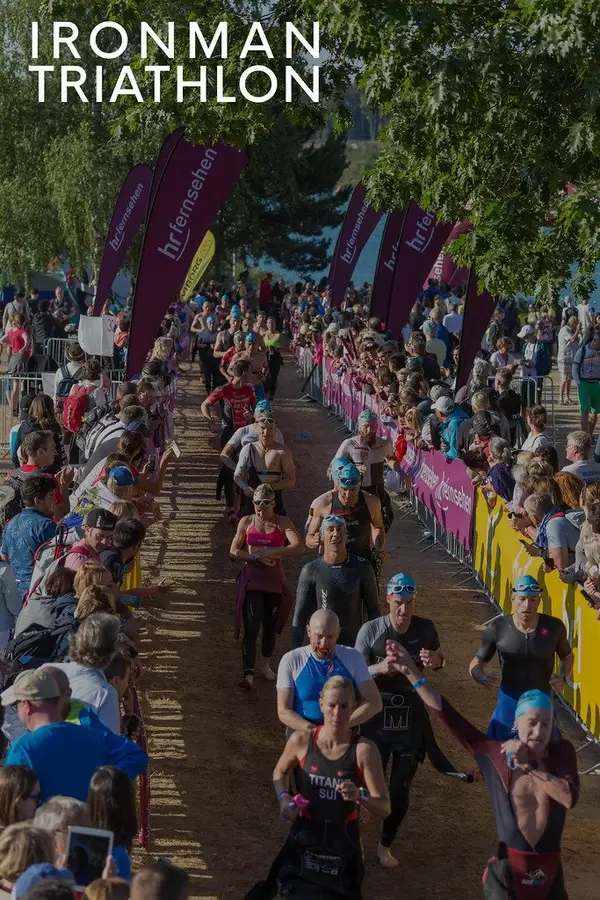 Ironman Triathlon Teilnehmer in Schwimmanzügen mit Badekappen, kaufen zwischen den Zuschauern entlang