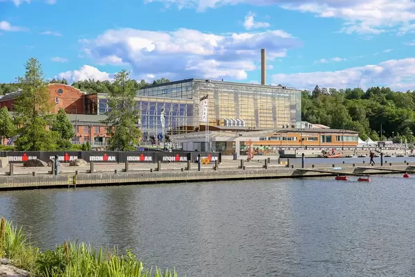Ironman-Werbung vor dem Glasgebäude und Konzerthaus "Sibelius-Halle" in Lahti, Finnland, neben Lahden Sataman Helmet am Vesijärvi-See