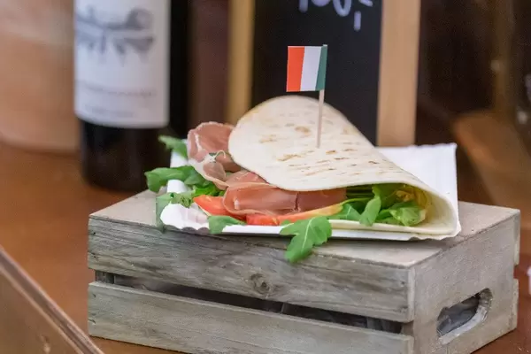Italian food: Piadina Romangola with Parma ham, salad, cream cheese, pesto and fresh  tomatoes on a wooden box