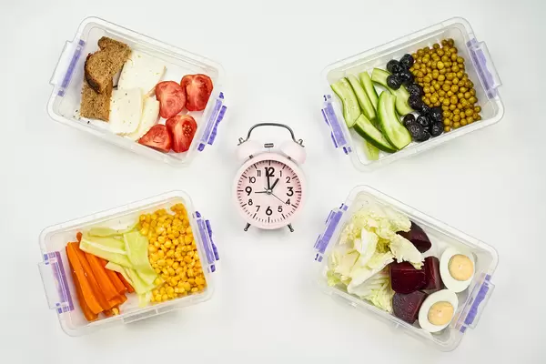 It's lunchtime. Alarm clock and food in lunchboxes