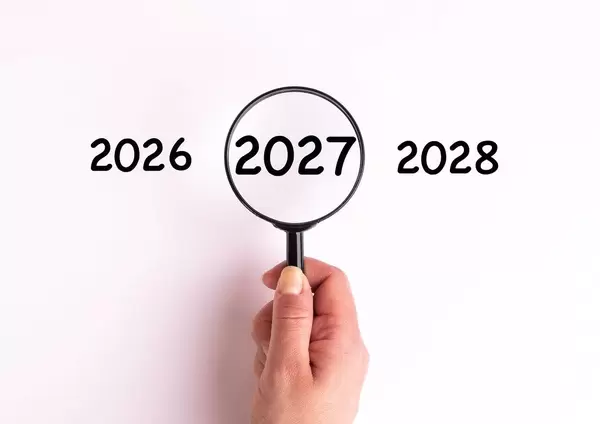 Jahreszahl 2027 auf weißer Oberfläche unter einer Lupe dargestellt