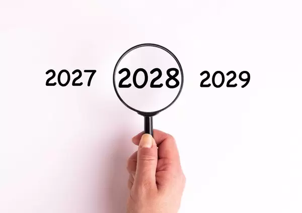 Jahreszahl 2028 auf weißer Oberfläche unter einer Lupe dargestellt
