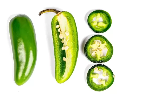 Jalapeno pepper halves and slices on a white background, top view