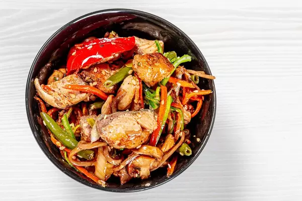 Japanese buckwheat noodle soba with vegetables, diced tuna, sauce and mushrooms in white bowl. Top view