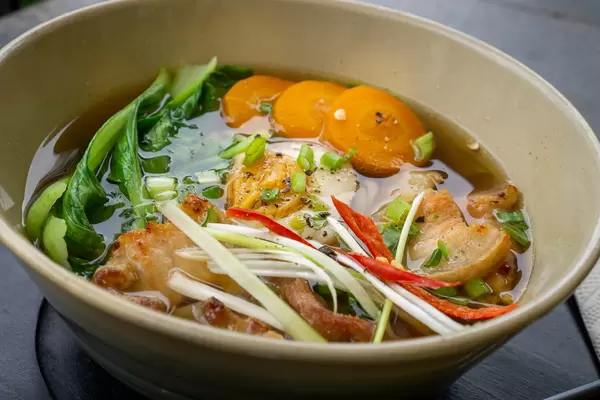 Japanisches Gericht Ramen Nudelsuppe mit frischem Gemüse, Chili und Schweinefleisch in einer Keramikschüssel Nahaufnahme