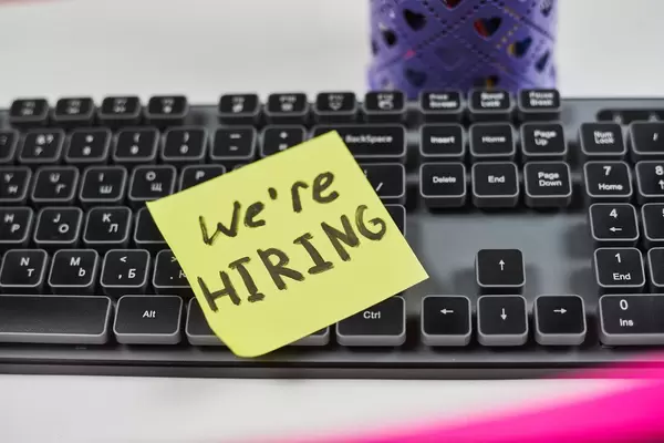 Job recruiting advertisement. We are hiring - phrase written on the sticky note