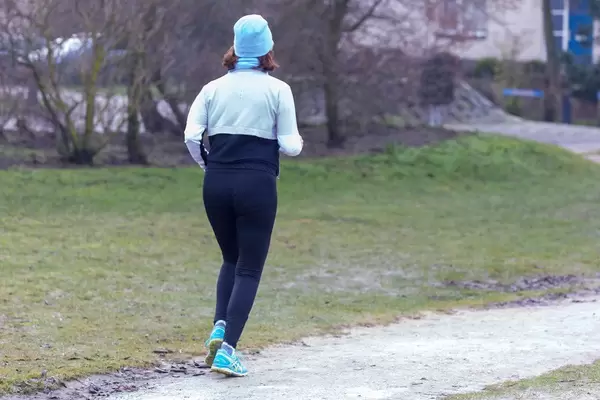 Joggende Frau mit langer Sportkleidung, trainiert bei kalten Temperaturen