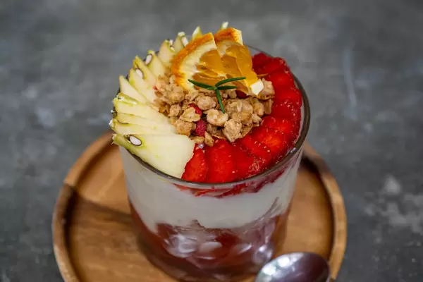 Joghurt mit Müsli, geschnittenen Äpfeln und Erdbeeren in einem Glas Nahaufnahme