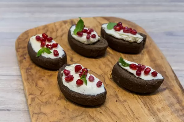 Johannisbrot mit Sahne und Granatapfelkernen auf einem hölzernen Brett