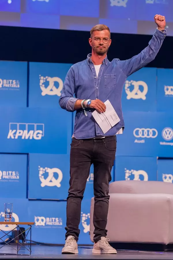 Joko Winterscheidt cheers the audience from the Center Stage of the Bits & Pretzels event at the International Congress Center in Munich