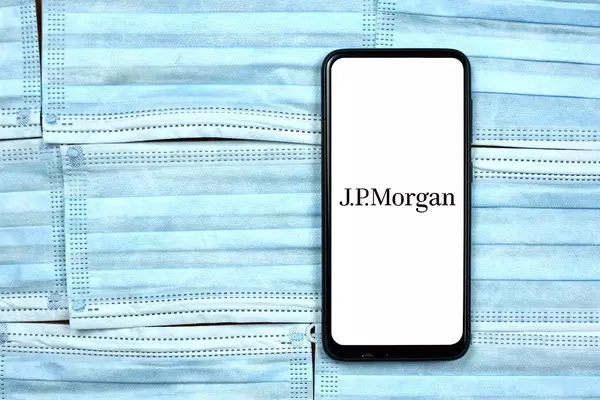 JPMorgan logo on smartphone screen over the face masks. Global company during coronavirus crisis