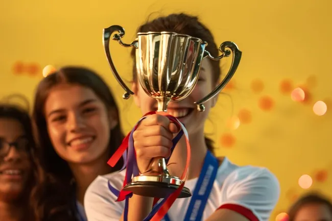 Jubelnd mit Pokal auf Siegertreppchen