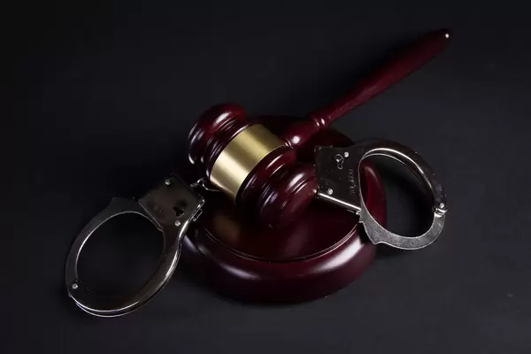 Judge's gavel and handcuffs on black background